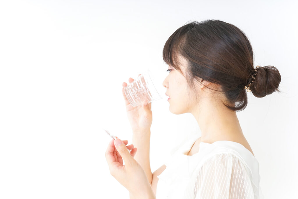 水で薬を飲む女性