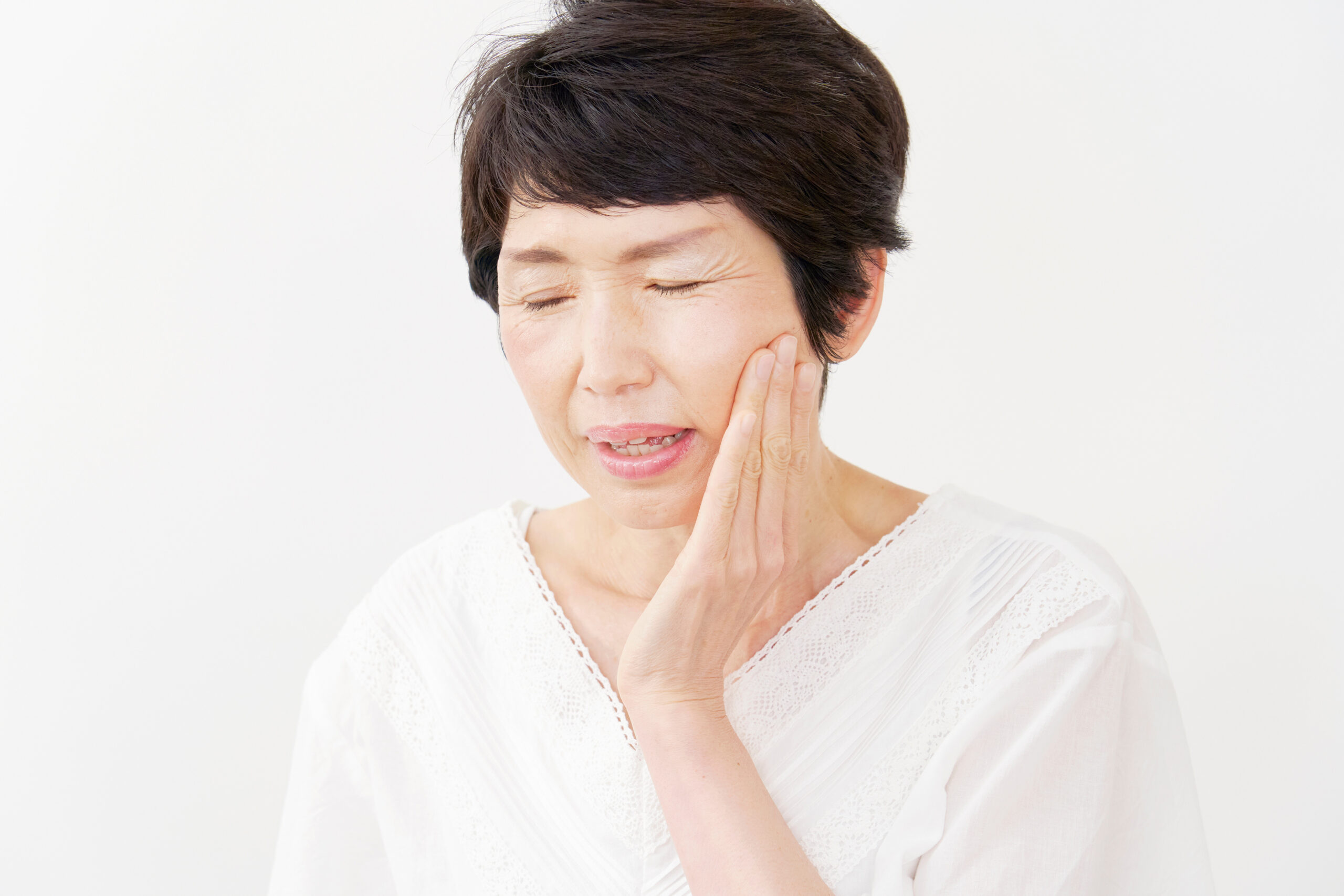 歯の痛みから頬を抑える中年女性