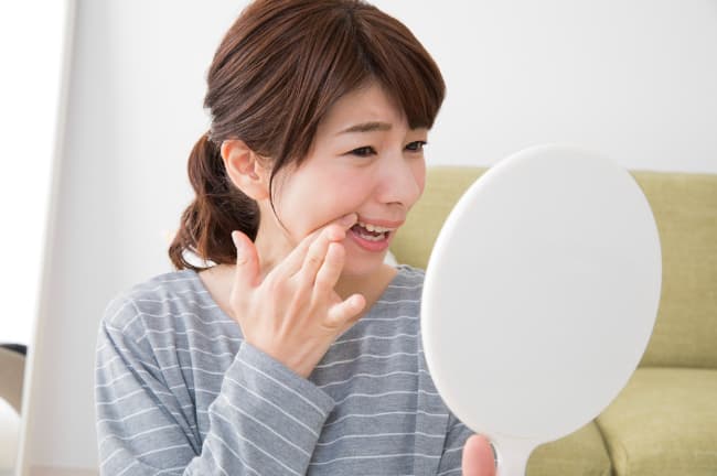 虫歯が気になって鏡を見る女性