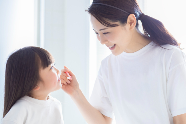 子どもの仕上げ磨きをする母親