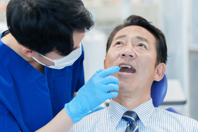 歯科医に歯を検診してもらう男性