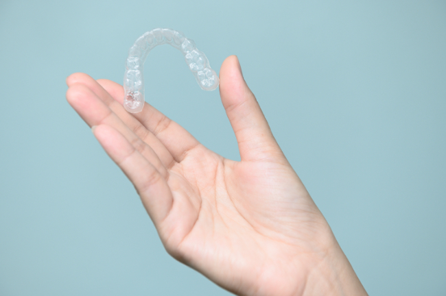 歯の矯正に使用するマウスピースを持つ手