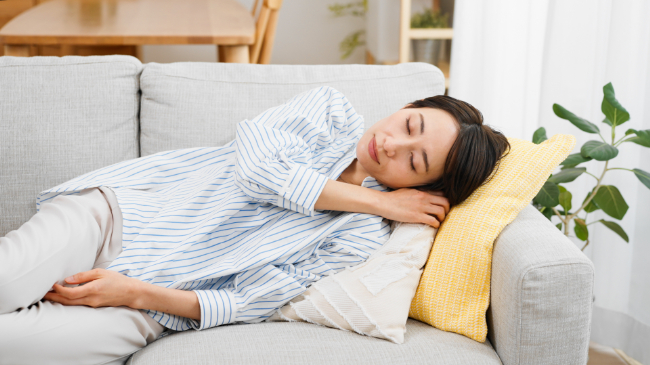 親知らず周辺に痛みを感じたため横になって安静にする女性