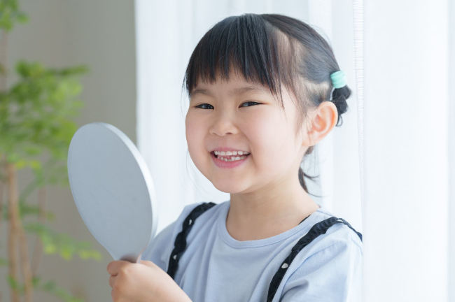 混合歯列期の歯を鏡で見る子ども