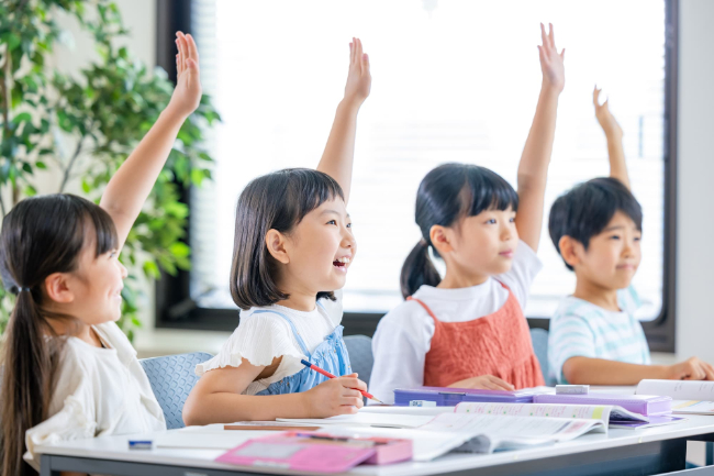 授業中に元気よく手を上げる小学生たち