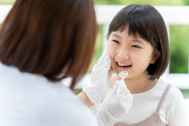 インビザライン・ファーストのために口腔内をチェックする子どもと歯科医師