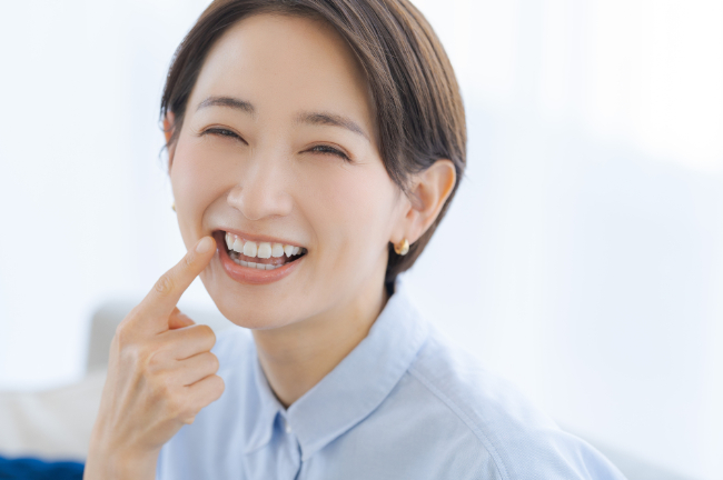 歯を指さして笑顔を見せる女性