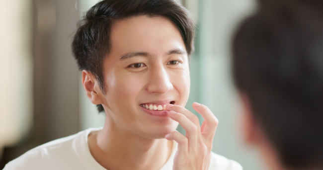 治療した前歯を鏡で確認する笑顔の男性
