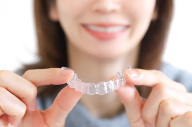 マウスピースタイプのリテーナーを両手で持つ女性