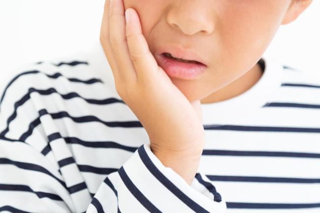 床矯正が痛くて頬を押さえる子ども