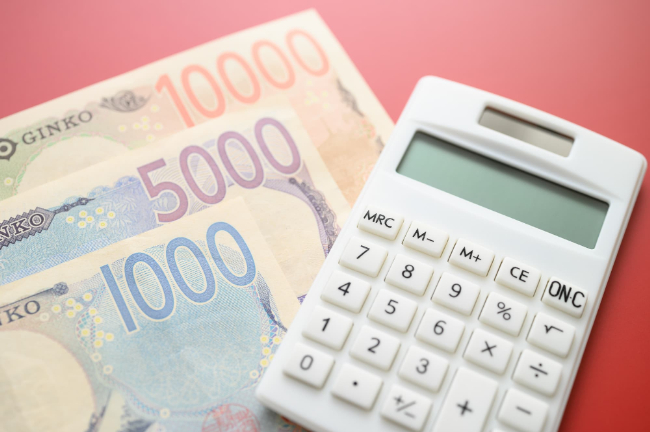 インビザラインで八重歯を治す場合にかかる費用を示す計算機と紙幣