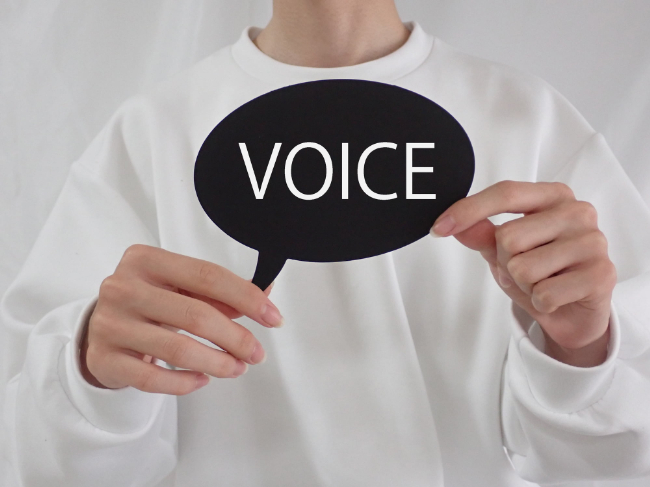 患者様の声をしめすボイスの札を持つ人