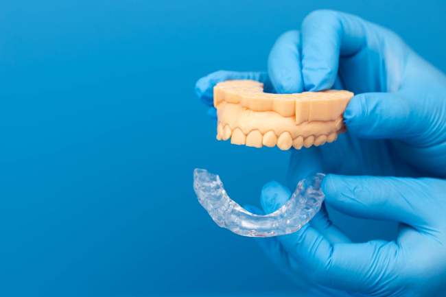 歯の模型とマウスピースを使って顎関節症の治療にスプリント療法をすすめるイメージ