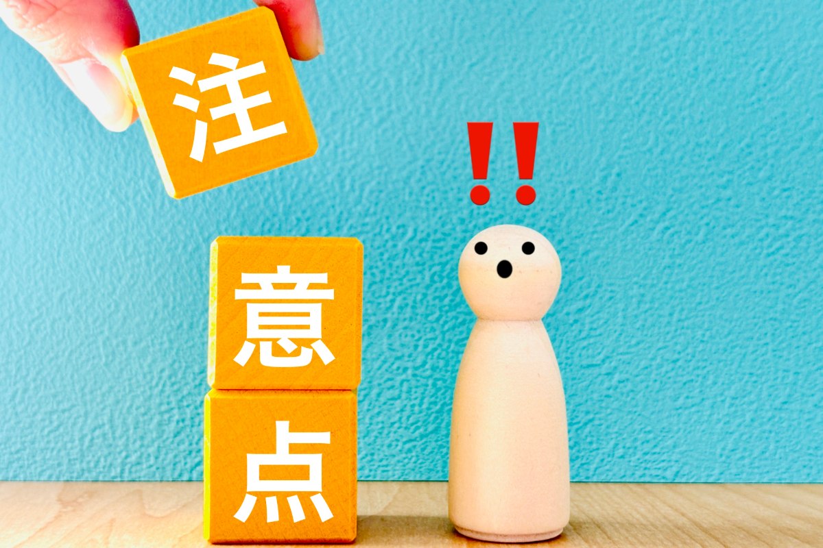 注意点と書かれたブロックを積む手を見て驚く人形
